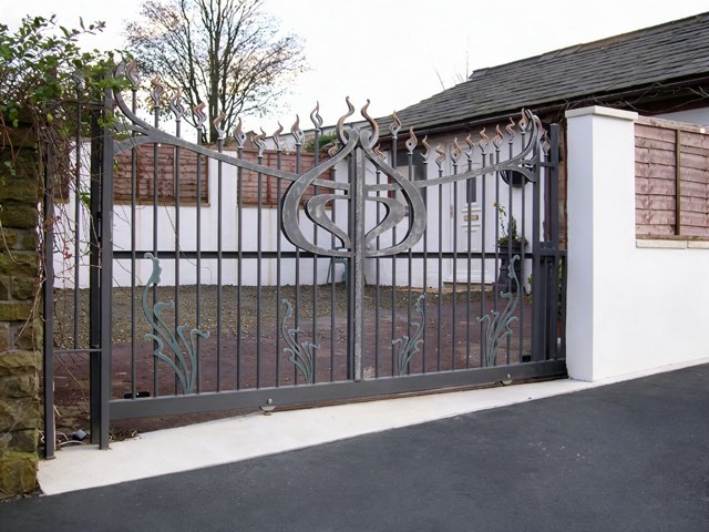 Art nouveau style wrought iron sliding gate with flame finials and leaf motifs