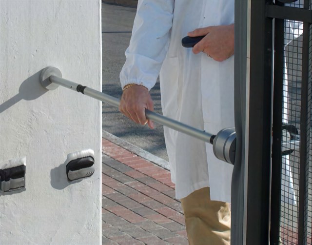Engineer force testing an automatic gate to BS EN 12453 with a hand-held force meter