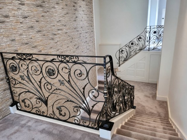 Ornate wrought iron staircase balustrade with scrolls, leaves and flower motifs