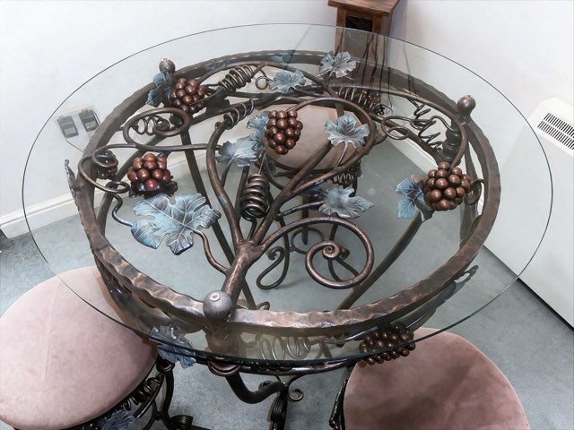 Wrought iron glass-topped table with hand-forged grapevine leaves and grapes