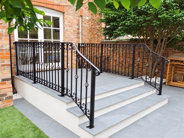 Wrought iron patio step handrail with basket-twist bars and scrolls on slate steps
