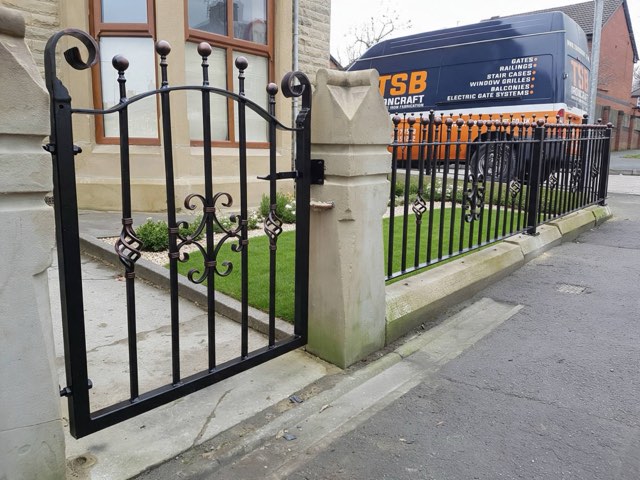 Wrought iron pedestrian gate and matching railings with ball finials beside a sandstone pillar and a TSB Ironcraft van